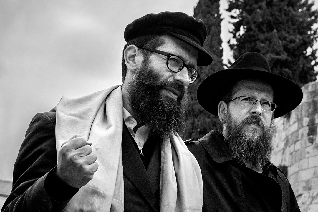 Two bearded men wearing hats and glasses.